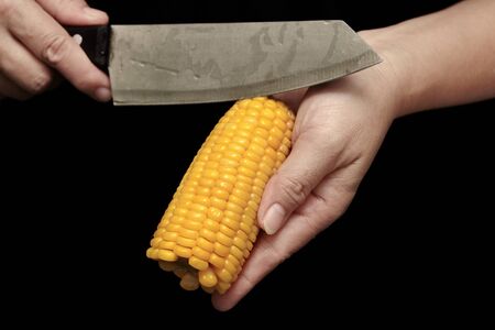 Delicious streamed sweet corn,which is going to be sliced by chef on black background.の写真素材