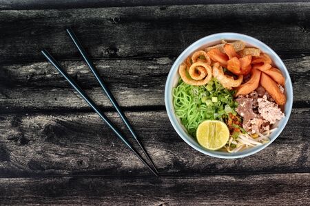 Green noodle with tom yam topped minced pork,chicken liver,fried sausage,halve lemon,bean sprouts, chili, pork rind and coriander.の写真素材