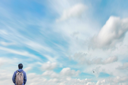 Tourist, backpacker standing looking at the beautiful sky with clouds and birdsの写真素材