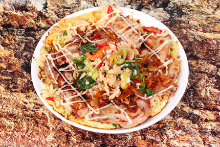 Homemade Japan pizza  (Okonomiyaki)  topped fried spicy basil with minced pork are fried mixed vegetable flour with meat topped sweet sauce ,mayonnaise and topped Thai popular foodの写真素材