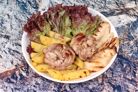 Chicken drumstick steak wrapped rice with  butter potato, oyster mushrooms and lettuce served on white plate.の写真素材
