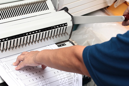 Binding documents ,Use your left hand to push the paper into the drill and used his right hand to...