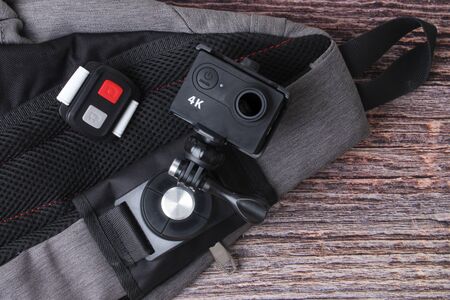 Ready backpack and 4K action camera with clip and remote on old wood  for travelling.