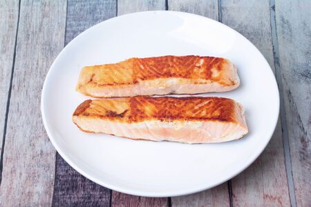 Isolated of 2 Grilled salmon steaks on white plate served on wood.の写真素材
