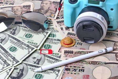 Passport ,eye glasss,small relax hat ,mirrorless camera,stylus, and mobile socket sim place on banknote for the time of relaxation and tourism, Essential vacation items, Travel concept background.の写真素材
