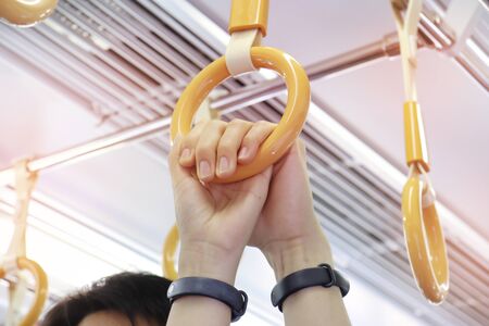 Man's hand holding a woman's hand on  circle handle on the train during the journey.の写真素材