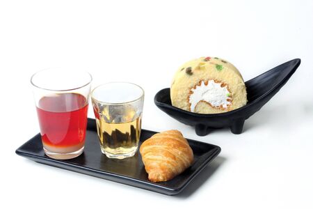 Thai Traditional milk tea served with tea, croissant and roll fruit cake served on white background.の写真素材