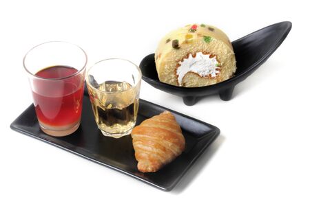 Thai Traditional milk tea served with tea, croissant and roll fruit cake served on white background.の写真素材
