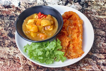 Ready served of crispy fried dolly fish with Japanese yellow curry topped green oak.の写真素材