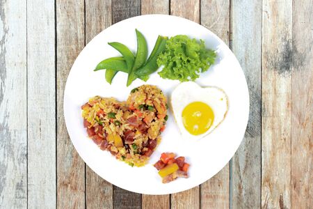 Isolated of  Colorful Chinese sausage fried rice and sunny egg in heart shapes with mixed vegetable as peas, pumpkin, taro, tomatoes, carrots and sweet peppers.の写真素材
