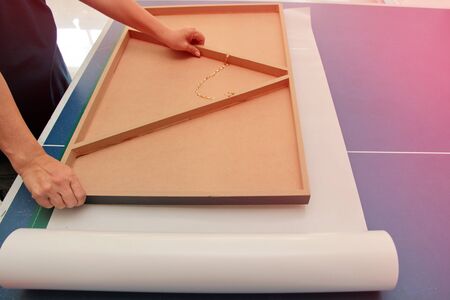 Photo frame technician is placing the floating frame over the double sided adhesive. To stick...