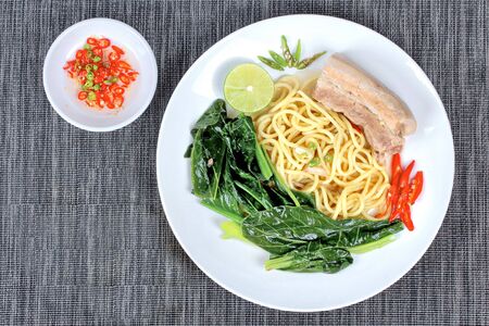 Ramen ,Japanese noodle, topped Chinese kale and streamed streaky pork in soup with halve green lemon and sliced chili and minced chili .の写真素材