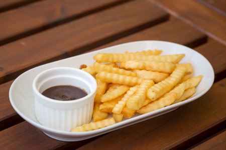 Fresh fried french fries with ketchup on wooden background