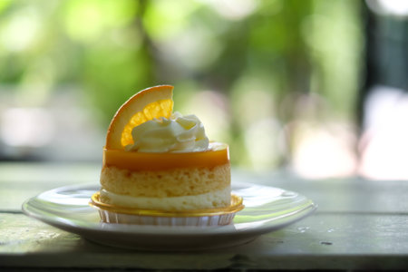 orange cake with orange topping and whipped cream in white dish on wooden topの写真素材