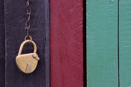 antique brass padlock hanging on a wooden doorの写真素材