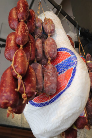 Raw Iberian ham leg hanging with salami in an Argentinean grocery storeの写真素材