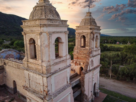 An aerial view of the church in Ambil, La Rioja, at sunset. The bell tower appears leaning and damaged, with the Riojan mountains forming the backdropの写真素材