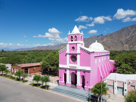The Church of Our Lady of Candelaria in Copacabana, Tinogasta, a haven of peace with its pink facade under the vast blue sky, framed by Catamarca's imposing geography.の写真素材
