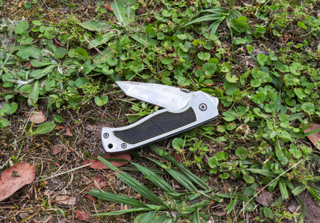 Folding pocket knife with non slip handle on dirt and leaves. Multi purpose tool for hiking and...