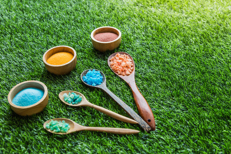 Spa salt in wooden spoon and cup lay on the green grassの写真素材