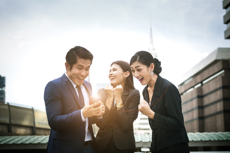 Three business officer happy after watch news from smart phoneの写真素材