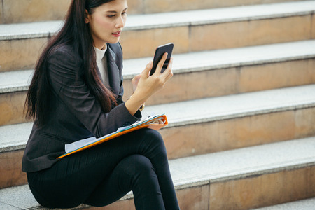 business woman use technology smart phone sit on outdoor stepの写真素材