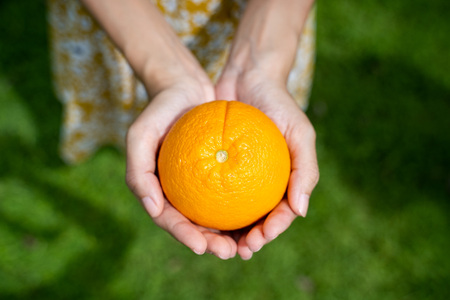 An girl hands present a fresh orangeの写真素材