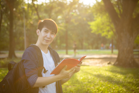 Portrait of high school boy with books and bag in park, education conceptの写真素材