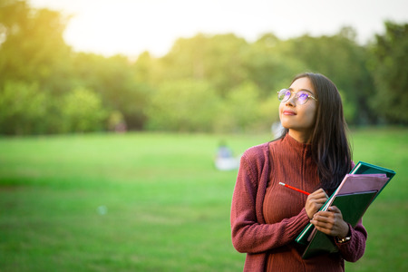 Portrait of high school girl with books in park, education conceptの写真素材