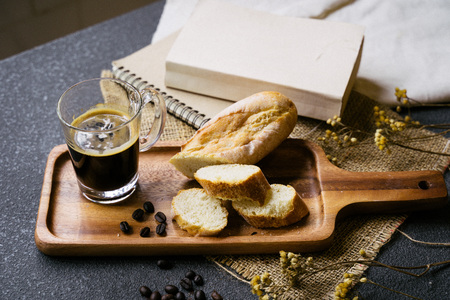 A coffee, bread, wood plate and book setting on black backgroundの写真素材