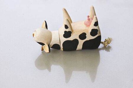 An overturned wooden cow toy on white background.の写真素材