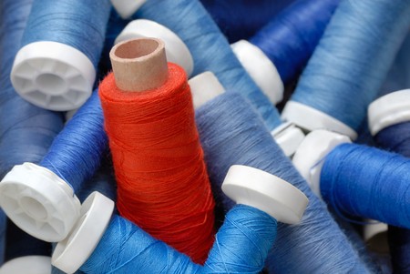Concept shot with a heap of blue bobbins and a red one standing out