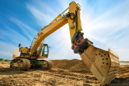 Big excavator on new construction site, in the background the blue sky and sunの写真素材