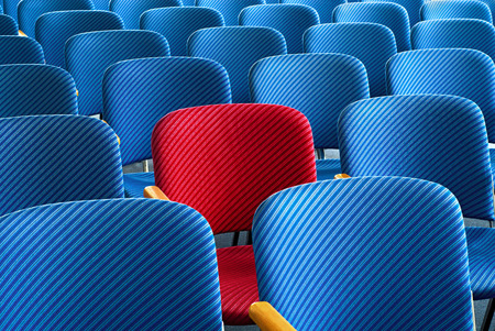 Red seat as an eyecatcher in the middle of rows of empty blue seats, conceptual imageの写真素材