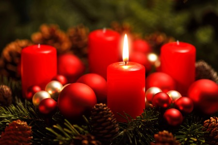 Low-key studio shot of a nice advent wreath with baubles and one burning red candleの写真素材