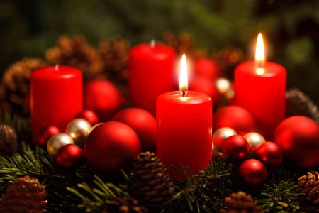 Low-key studio shot of a nice advent wreath with baubles and two burning red candlesの写真素材