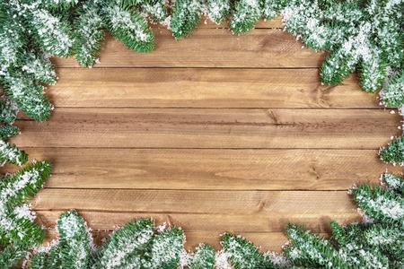 Wood planks background framed with snow covered fir twigsの写真素材