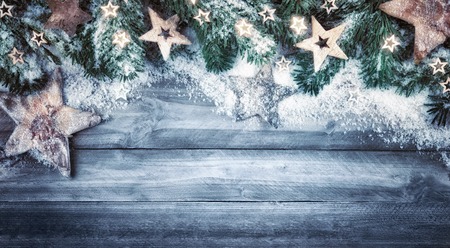 Blue gray Christmas background in natural wood style, rustic, simple and stylish, with a border of fir branches, wooden stars and snowの写真素材