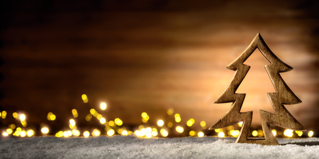Cozy Christmas arrangement with beautiful wooden ornaments on snow in the warm candlelight of a nice lantern, low-key studio shotの写真素材