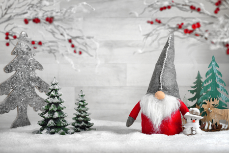 Ornamental arrangement for winter and Christmas, with a Santa puppet, snowman, reindeers and trees on snowの写真素材