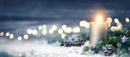 Christmas decoration with candle, lights, fir branches and ornaments on snow, panoramic formatの写真素材