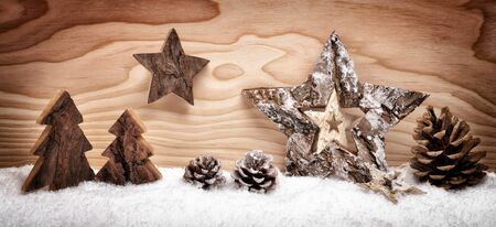 Festive Christmas arrangement with beautiful wooden ornaments on snow in front of a wood board background, studio shotの写真素材