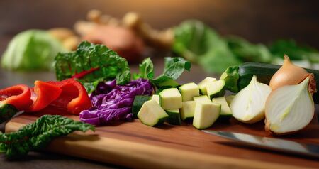 Cooking vegetables on a wooden cutting board. A closeup with shallow focus showing colorful, nutritious and delicious food ingredients as a healthy lifestyle concept.の写真素材