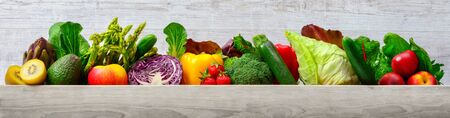 Arrangement of fruits and vegetables in many appetizing colors in a row on wooden light gray background, concept for a healthy plant-based lifestyle and fitness, with copy spaceの写真素材