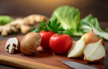 Preparing vegetables on a wooden cutting board to cook. A closeup with shallow focus showing...