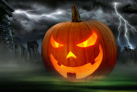 Glowing Jack o Lantern in a dark graveyard with lightning bolts in the night skyの写真素材