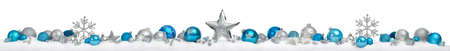 Christmas border or banner with stars and baubles arranged in a row on snow, silver and blue, extra wide and isolated on white backgroundの写真素材