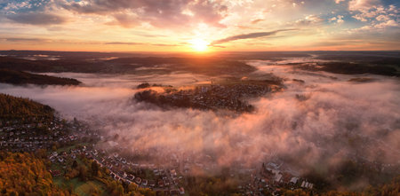 Glorious sunrise over the mist, an aerial panorama of a town on a majestic morningの写真素材
