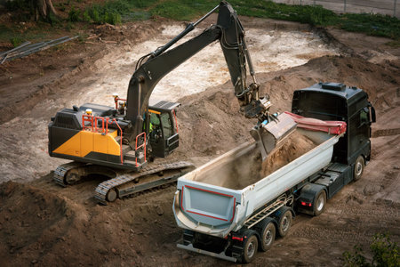Excavator loading dirt into a dump truck on a construction site, nice view from aboveの写真素材