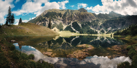 Mountain scenery with reflections in a beautiful lake, blue sky and white clouds, located in Bavaria, Germanyの写真素材